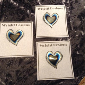 May include: Three cards with the text "Wright Designs" printed on them. Each card features a heart-shaped metal pin with a blue and gold iridescent finish.