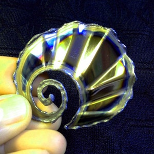 May include: A silver-colored metal spiral with a fan-shaped design. The spiral is made of a thin metal and has a shiny finish. The fan-shaped design is made of a thicker metal and has a matte finish.