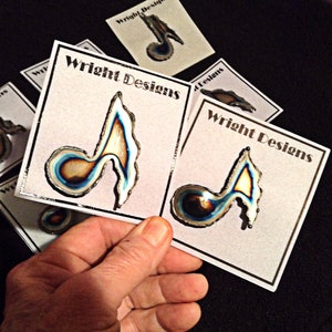May include: A set of five cards with the text "Wright Designs" printed on them. Each card features a unique, colorful, metal music note design.