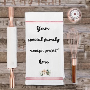 May include: White kitchen towel with pink stripes and a floral design. The text "Your special family recipe print here" is printed in black on the towel.