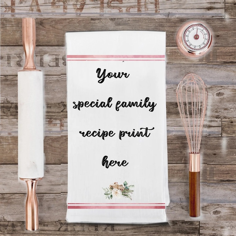 May include: White kitchen towel with pink stripes and a floral design. The text "Your special family recipe print here" is printed in black on the towel.