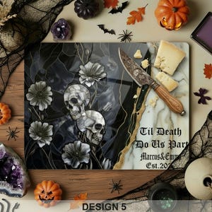 May include: A decorative cutting board with a skull and floral design, a cheese knife, and cheese. The board has the text "Til Death Do Us Part" and "Marcus & Emma Est. 2023". The design is in black, white, and gold.