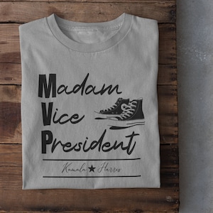 May include: Gray t-shirt with the text "Madam Vice President" and a black and white illustration of a pair of sneakers. The text "Kamala Harris" is below the sneakers.