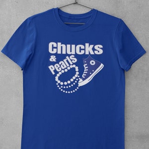 May include: A royal blue t-shirt with the text "Chucks & Pearls" in white lettering. A white pearl necklace is wrapped around a blue Converse shoe.