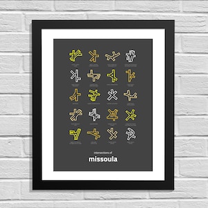 May include: Framed print featuring a dark gray background with a grid of stylized road intersection diagrams in yellow and white. The text "intersections of missoula" is at the bottom. The print is in a black frame.