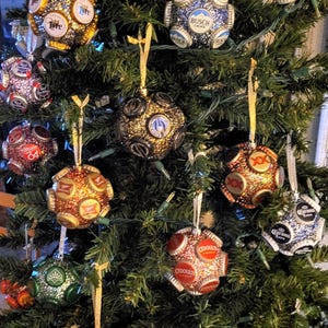 Puede incluir: Un &aacute;rbol de Navidad decorado con adornos hechos a mano a partir de tapas de botellas de cerveza. Los adornos est&aacute;n cubiertos de purpurina y presentan varias marcas de cerveza, entre ellas Budweiser, Miller Lite, Busch Light, Corona y O'Douls.