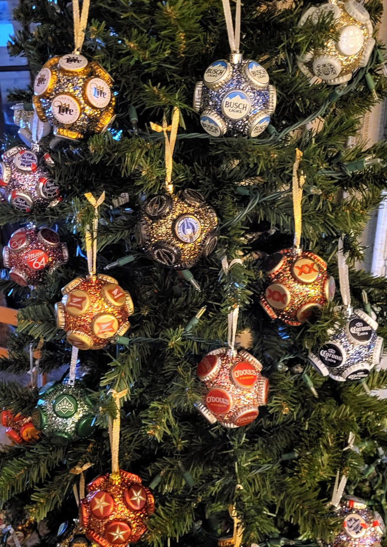 Puede incluir: Un &aacute;rbol de Navidad decorado con adornos hechos a mano a partir de tapas de botellas de cerveza. Los adornos est&aacute;n cubiertos de purpurina y presentan varias marcas de cerveza, entre ellas Budweiser, Miller Lite, Busch Light, Corona y O'Douls.