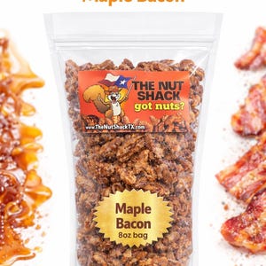 Puede incluir: Una bolsa de pl&aacute;stico transparente llena de nueces con sabor a arce y tocino. La bolsa tiene una etiqueta dorada con la inscripci&oacute;n "Maple Bacon 8oz bag". El logotipo de The Nut Shack, con una ardilla y la bandera de Texas, es visible. Tambi&eacute;n se muestra el texto "The Nut Shack got nuts?"