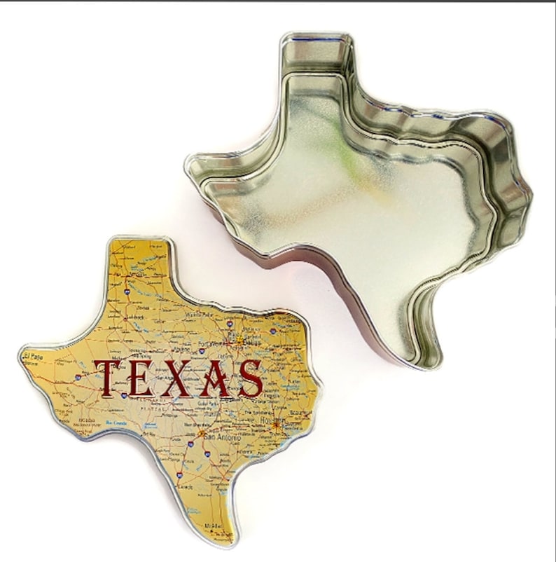 Puede incluir: Una lata con forma de Texas con un dise&ntilde;o de mapa y la palabra "TEXAS" en granate. La lata est&aacute; abierta, revelando su interior. La tapa presenta un mapa de Texas.