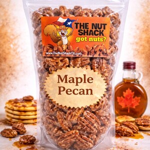 K&ouml;nnte beinhalten: Eine transparente Plastikt&uuml;te gef&uuml;llt mit Ahorn-Pekan-N&uuml;ssen. Das Etikett tr&auml;gt die Aufschrift "The Nut Shack got nuts?" mit einem Cartoon-Eichh&ouml;rnchen. Eine Flasche Ahornsirup und Pfannkuchen sind im Hintergrund zu sehen.