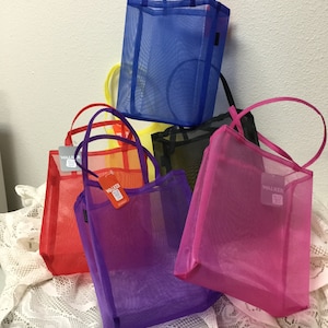 May include: Five mesh tote bags in different colors: blue, yellow, black, red, and purple. The bags have a black label with the word "WALKER" on them.
