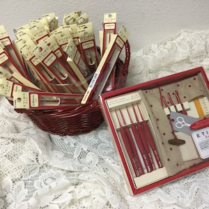 May include: A set of red crochet hooks in a red and white box with a beige fabric pouch. The box includes a pair of scissors and a ruler. The crochet hooks are labeled with their sizes in millimeters. The box also includes the text "ETIMO Red" and the logo for "Hobby Lobby".