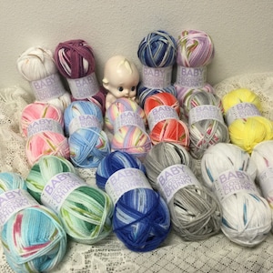 May include: A collection of 16 colorful skeins of Baby Blossom Chunky yarn. The yarn is multi-colored and includes shades of pink, blue, green, yellow, red, and grey.