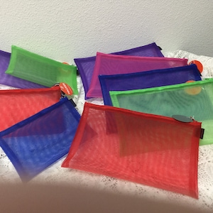 May include: Assortment of colorful mesh zippered pouches. The pouches are made of a see-through mesh material and come in a variety of colors, including red, green, blue, and purple.
