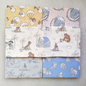 May include: Six fabric squares with different patterns featuring characters from the Disney movie The Jungle Book. The patterns include a yellow square with a baby elephant in a parachute, a pink square with a baby elephant, a white square with a baby elephant, a white square with a baby zebra, a grey square with a baby elephant, and a blue square with a baby elephant.