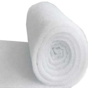 May include: A roll of white, fluffy batting material. The batting is tightly rolled, with the end of the roll visible, and a portion of the flat material extending to the left. The material appears soft and lightweight.