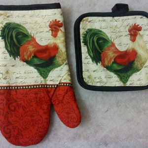 May include: A red and green rooster oven mitt and a matching pot holder. The mitt has a red and white paisley pattern on the back. The rooster is on a cream background with black script.