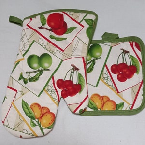May include: A set of two green and white oven mitts with a fruit print. The mitts feature cherries, plums, and limes.