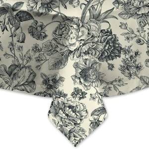 May include: A cream-colored tablecloth featuring a detailed floral pattern in shades of gray and black. The design includes large peony blooms, leaves, and smaller floral elements, creating a classic, elegant aesthetic. The fabric drapes over a surface, showcasing the pattern.