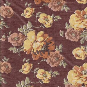 May include: A brown fabric with a floral pattern. The flowers are yellow, orange, and pink. The fabric has a textured surface.