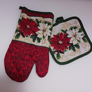 May include: A set of two red and white Christmas-themed oven mitts. The larger mitt has a red background with a white damask pattern. The smaller mitt has a white background with a red and white poinsettia pattern.