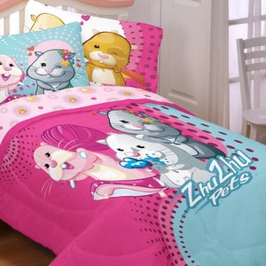 May include: A bedding set featuring a pink and blue comforter and pillowcases with cartoon hamsters. The comforter has the text "Zhu Zhu Pets" and a design of hamsters. The pillowcases have a light blue background.