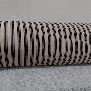 May include: A roll of off-white fabric with black stripes. The fabric is woven and has a subtle texture.