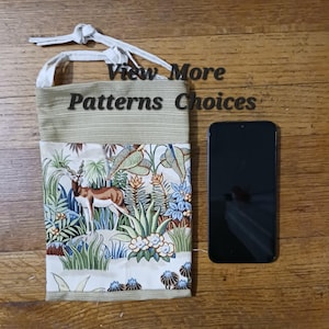 May include: A beige and brown fabric pouch with a drawstring closure. The pouch features a colorful print of a deer in a jungle scene. The text "View More Patterns Choices" is visible on the pouch. A black smartphone is next to the pouch.