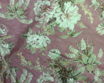 May include: A pink and green floral fabric with a repeating pattern of flowers and leaves. The fabric has a textured surface and a subtle sheen.