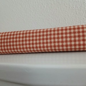 May include: A roll of orange and white gingham fabric.