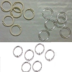 May include: A set of eight silver metal curtain rings. The rings are all the same size and have a smooth, polished finish.