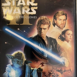May include: DVD case for Star Wars Episode II: Attack of the Clones. The case features a blue lightsaber, Yoda, Anakin Skywalker, Obi-Wan Kenobi, and Padmé Amidala.