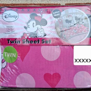 May include: A pink Twin sheet set featuring Minnie Mouse. The set includes a flat sheet, fitted sheet, and a standard pillowcase. The sheets have a pattern of large white polka dots and pink hearts. The package is sealed in plastic.