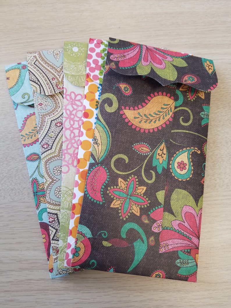 May include: A set of five colorful patterned envelopes with a paisley design. The envelopes are all different colors and patterns, but they all have a similar paisley design.