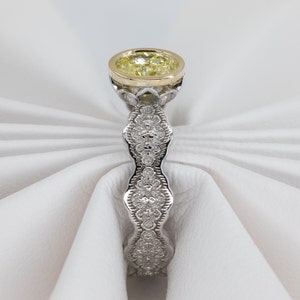 May include: A yellow diamond engagement ring with a delicate, intricate, and detailed band of pave set diamonds. The ring is set in white gold with a yellow gold setting for the center stone.