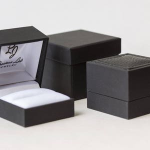 May include: Three black ring boxes. The largest box has a white interior and the text "Precious Lace Jewelry" printed on the inside of the lid.