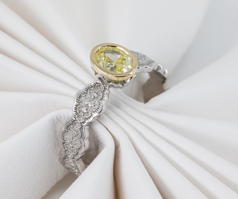 May include: A yellow oval gemstone ring with a gold setting and a white gold band. The band is decorated with small diamonds.