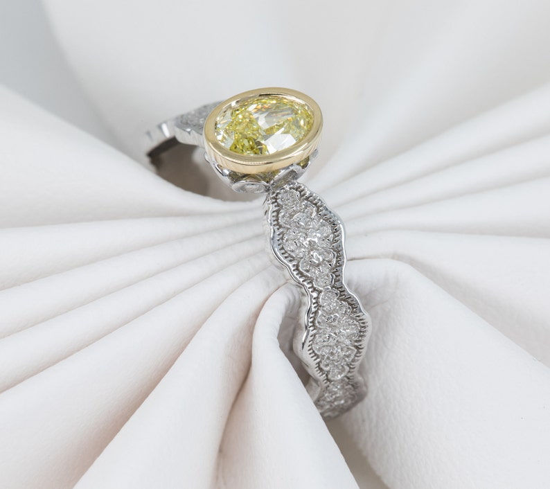 May include: A silver ring with a yellow oval-shaped gemstone set in a gold bezel. The band is decorated with small diamonds.
