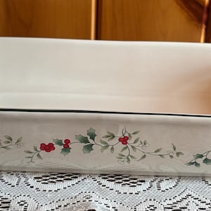 May include: Rectangular white ceramic baking dish with a black trim and holly berry design. The dish has a capacity of approximately 3 quarts and is suitable for baking casseroles and other dishes.