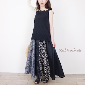 May include: A sleeveless black top with a scalloped neckline paired with a long, flowing skirt. The skirt features panels of patterned fabric in blue, black, and white. The text "Real Handmade" is visible on the right side.