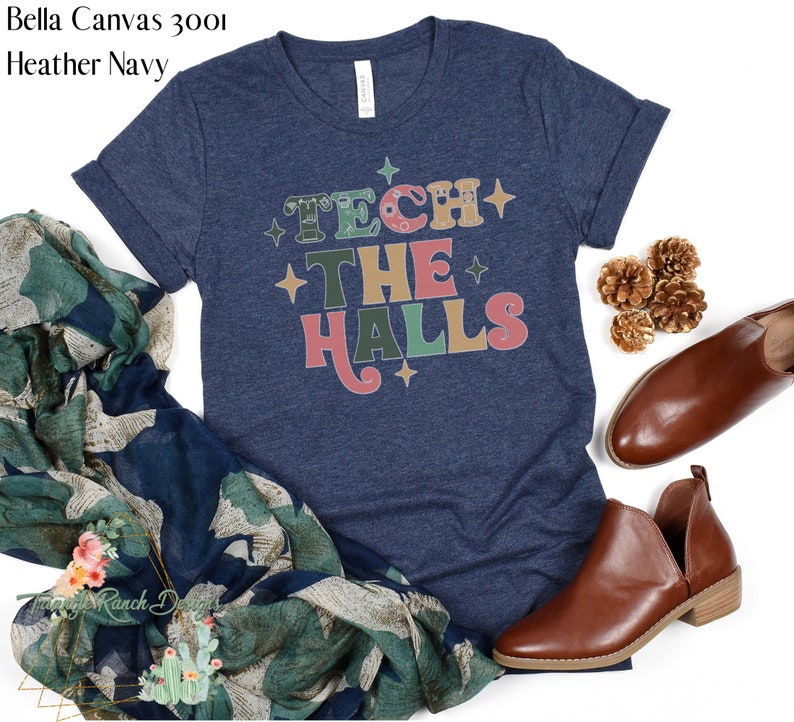 May include: A heather navy blue t-shirt with the text "Tech the Halls" in colorful retro lettering. The text is surrounded by small white stars.