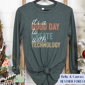 May include: A dark green long-sleeved t-shirt with the text "it's a GOOD DAY to CREATE with TECHNOLOGY" in a vintage style font.