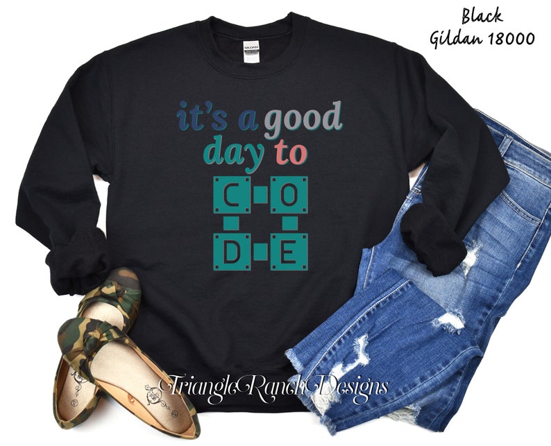 K&ouml;nnte beinhalten: Schwarzes Sweatshirt mit dem Text "it's a good day to CODE" in Blau- und Gr&uuml;nt&ouml;nen. Das Design zeigt ein gitterartiges Muster mit den Buchstaben C, O, D und E. Das Sweatshirt wird mit blauen Jeans gezeigt.