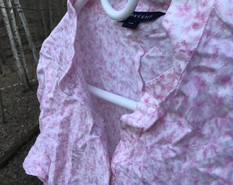 May include: A pink and white floral button-up shirt with a white collar and a small tag that says "OSIEN" on the front.