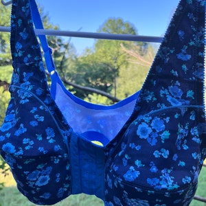May include: A blue floral print bra with adjustable straps and a front closure. The bra has a mesh lining and a smooth, comfortable feel.
