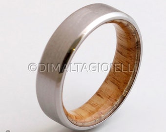 May include: A silver ring with a wood inlay. The wood is a light brown color and has a natural grain pattern. The ring is a simple design with a beveled edge.