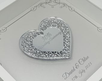 May include: A framed, silver-colored heart-shaped ornament for a 30th wedding anniversary. The ornament is set against a light gray background with decorative flourishes and the names "David & Chloe" and the date "27th July 2023".