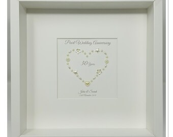 May include: A framed white artwork celebrating a pearl wedding anniversary. The artwork features a heart shape made of pearls, with the words "Pearl Wedding Anniversary" and "30 Years" displayed. The names "John & Sarah" and the date "21st November 2018" are also included.