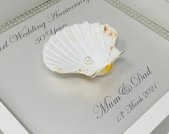 May include: A framed artwork featuring a white seashell with a pearl, set against a light gray background. The frame is white, and the text reads "Pearl Wedding Anniversary 30 Years" and "Mum & Dad 13th March 2021".