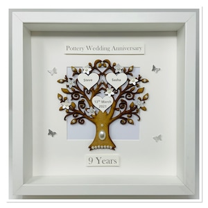 May include: A white frame containing a wooden tree design. The tree has two hearts with the names Steve and Sasha on them. The date 13th March 2021 is on a heart at the base of the tree. The text "Pottery Wedding Anniversary" and "9 Years" are also on the frame.
